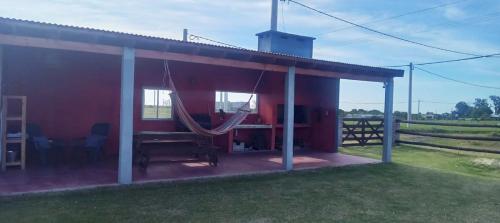 una casa rossa con un'amaca in un campo di AZUL Casa De Campo a Esquina