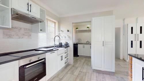 a white kitchen with white cabinets and a sink at Guernsey Home in Port Shepstone