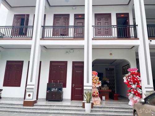 a white building with red doors and flowers on the steps at Trần Hưng Đạo 186 in Na Ngô