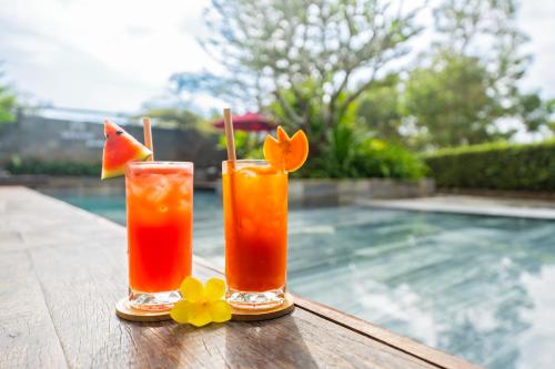 two cocktails on a table next to a swimming pool at Gia Huy Riverside Hotel Hoi An in Hoi An