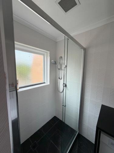 a shower with a glass door in a bathroom at Cozy 2BR apartment, Woden,Canberra , pet free, free parking in Lyons