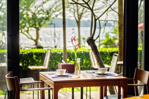 a wooden table with two cups and a flower on it at Gia Huy Riverside Hotel Hoi An in Hoi An