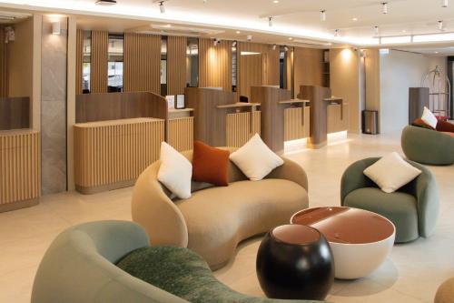 a lobby with couches and chairs in a building at Hotel Holm Bangkok in Bangkok