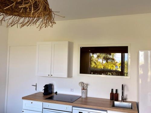 Una cocina con gabinetes blancos y un fregadero y una ventana. en Always Sun ,1 bdr up to 4 guests, en Baie Nettle