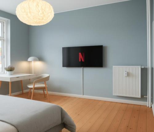 Un dormitorio con una cama y un televisor en la pared. en Danmarksgade Ensuites, en Aalborg