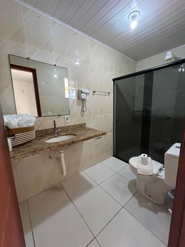 a bathroom with a toilet and a sink and a mirror at Pousada Luar in Santa Cruz Cabrália