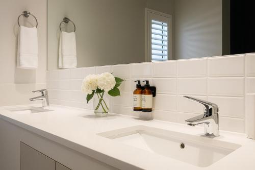 a white bathroom with two sinks and a mirror at The Max Hotel Sandton in Johannesburg