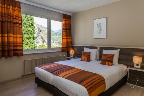 a bedroom with a large bed with a large window at Hotel Castel in Sion