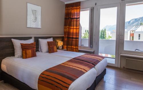 a bedroom with a large bed with a large window at Hotel Castel in Sion