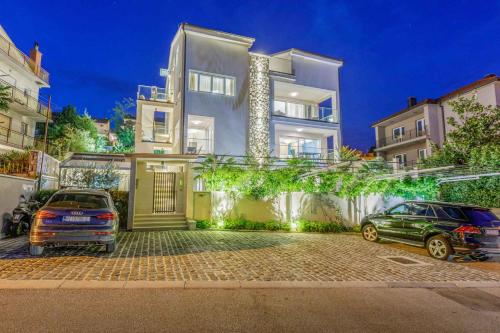 two cars parked in front of a large white building at Apartment in Crikvenica 41679 in Crikvenica