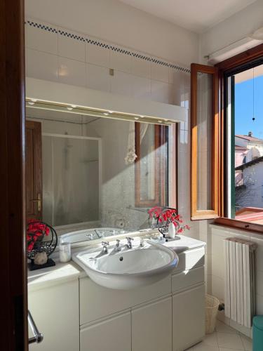 a white bathroom with a sink and a window at Joe's apartments in Carrara