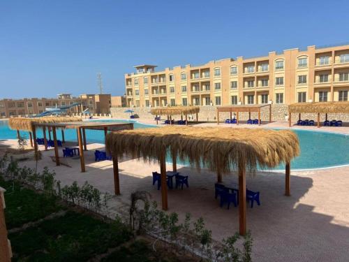 a resort with a pool with tables and straw umbrellas at Bay View Sahl Hasheesh Chalet in Hurghada