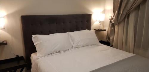 a bedroom with a bed with white sheets and pillows at Peaceful Casa in Kempton Park