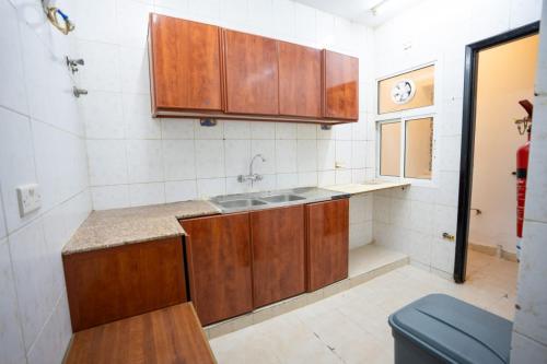 Una cocina con gabinetes de madera y un fregadero. en Mozna Hostel, en Mascate