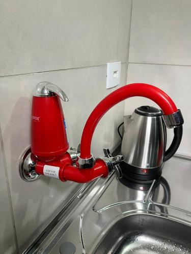 a red faucet over a sink with a tea kettle at Panama 90 - Studio - Região Central in Poços de Caldas