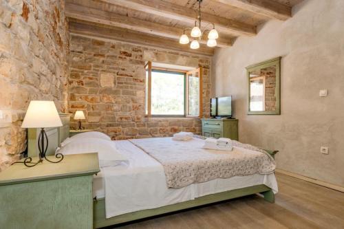 ein Schlafzimmer mit einem Bett und einer Ziegelwand in der Unterkunft Old Town Villa Hvar in Basina