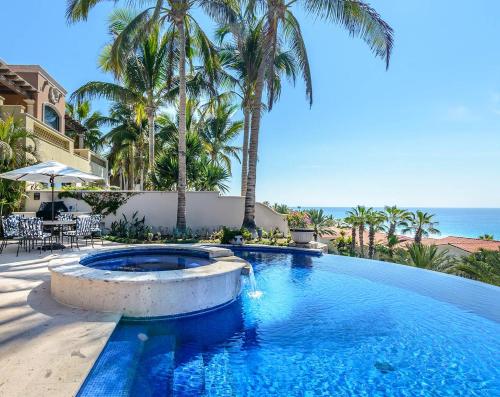 a swimming pool with palm trees and the ocean at Villa Pura Vida in San José del Cabo