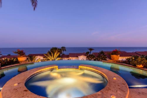a large swimming pool with the ocean in the background at Villa Pura Vida in San José del Cabo