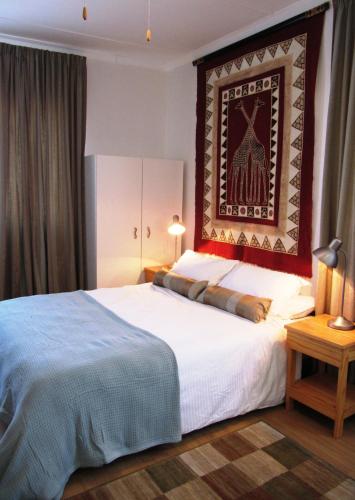 a bedroom with a large bed with a painting on the wall at Pebble Stone House Bed & Breakfast in Swakopmund
