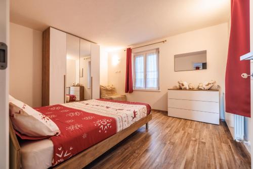 a bedroom with a bed and a dresser and a window at Casa Adamello in Corteno Golgi