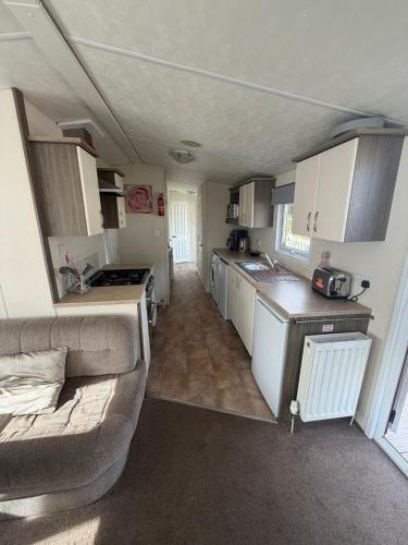 a small kitchen with a couch in a caravan at Sunnymede D1 - Hot Tub Caravan - Sleeps 10 - Fantasy Island, Ingoldmells - Meadow Lakes Caravan & Lodge Hire in Ingoldmells