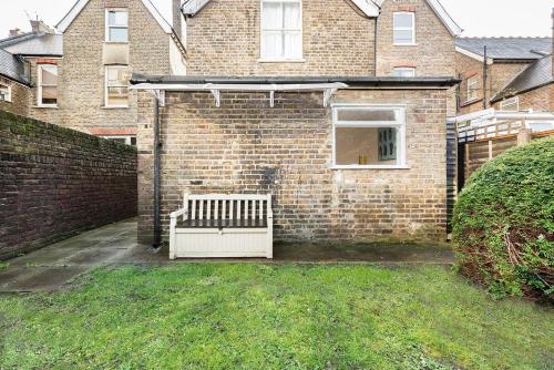 a brick house with a bench in a yard at Garden flat near Ealing Broadway in London