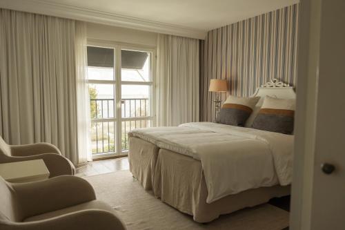 ein Schlafzimmer mit einem Bett und einem Stuhl und einem Fenster in der Unterkunft Ystad Saltsjöbad in Ystad