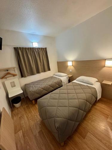 a hotel room with two beds and a window at Première Classe Rennes sud Est in Chantepie