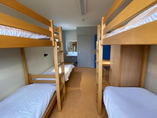 a room with three bunk beds and a hallway at Auberge de Jeunesse HI Pontarlier in Pontarlier