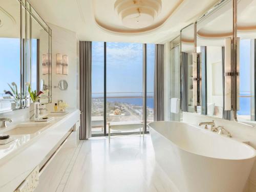 a white bathroom with two sinks and a large tub at Raffles Jeddah in Jeddah