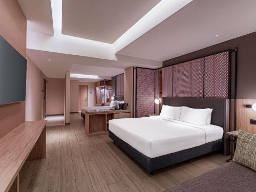 a bedroom with a large white bed and a desk at Grand Mercure Kuala Lumpur Bukit Bintang in Kuala Lumpur
