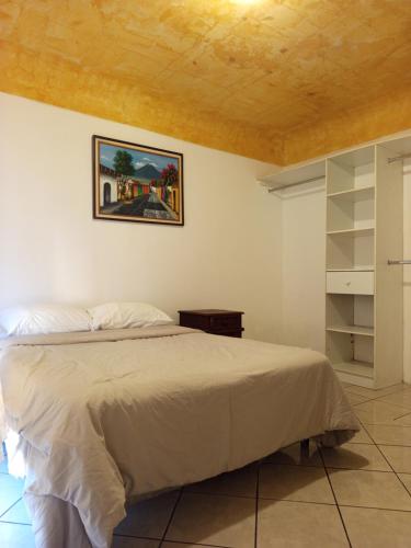 a bedroom with a bed and a painting on the wall at Antigua Encantó Colonial in Antigua Guatemala