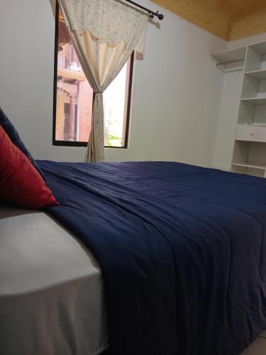 a bedroom with a blue bed with a window at Antigua Encantó Colonial in Antigua Guatemala