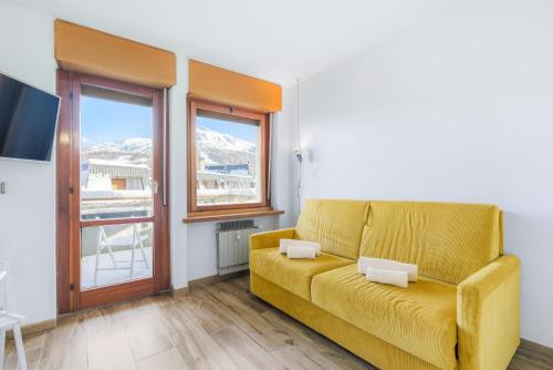 a living room with a yellow couch and a window at Hostdomus - Yellow Suite in Sestriere