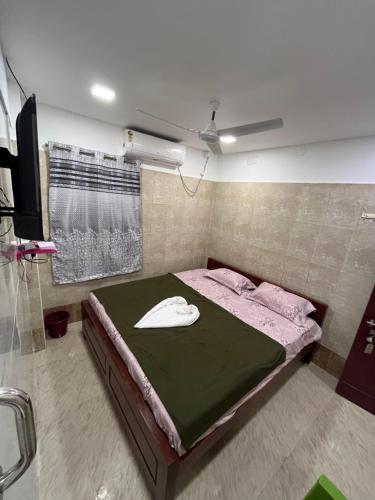 AR lodge في تيروفانمالي: غرفة نوم مع سرير مع قبعة عليه