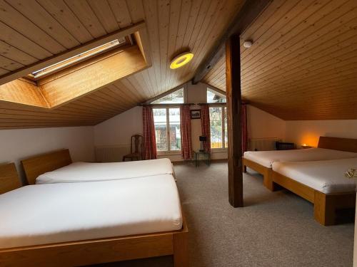 a bedroom with two beds in a room with a ceiling at Chalet Maithili Lauterbrunnen -152-Year-Old Majestic Chalet in Lauterbrunnen