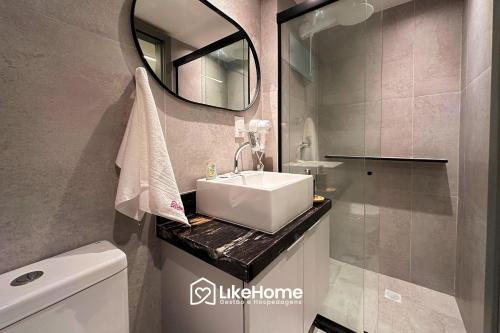 une salle de bains avec un lavabo et un miroir dans l'établissement Hit Cabo Branco - LikeHome Hospedagens, à Tambaú