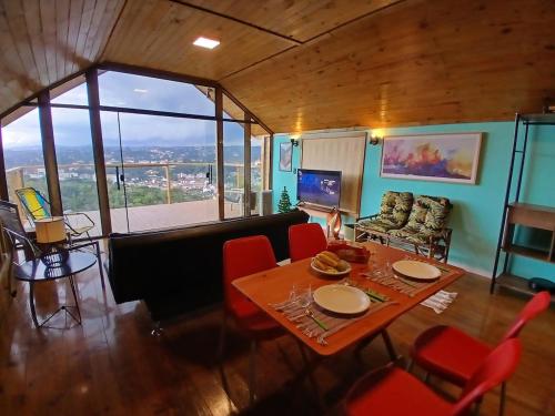 a living room with a table and red chairs at Scandinavian Lodge - Jacuzzi Privativa in Campos do Jordão