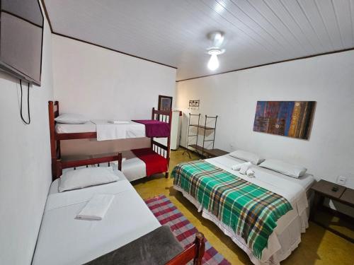a small room with two beds and a tv at Pousada Ecológica Bicho Preguiça in Trindade