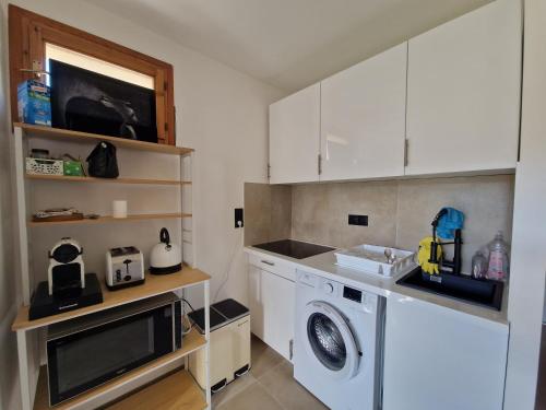 a kitchen with a washing machine and a microwave at Coquet 2 pièces neuf Calvi Plage in Calvi