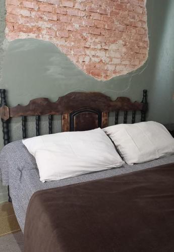 1 cama con almohadas blancas y pared de ladrillo en Casa75, en Socorro