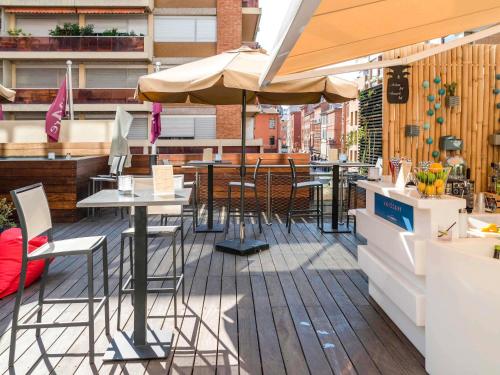eine Terrasse mit Tischen und Stühlen und einem Sonnenschirm in der Unterkunft Mercure Toulouse Centre Saint-Georges in Toulouse