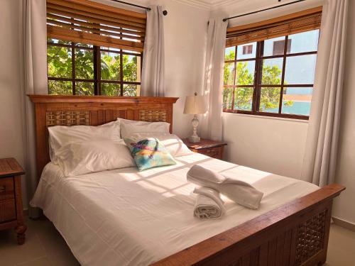 a bed with white sheets and a pair of shoes on it at Apartamento con Piscina 2 Habitaciones Cerca de la Playa Bavaro in Punta Cana