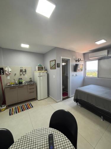a bedroom with a bed and a sink and a refrigerator at Loft funcional no centro! in Foz do Iguaçu