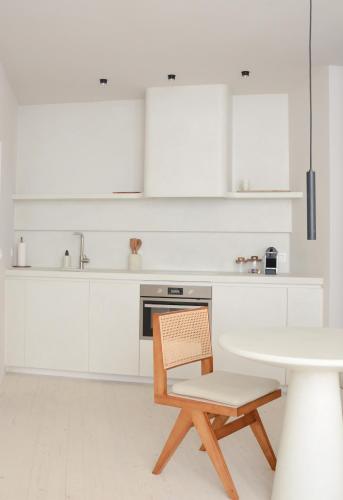 a white kitchen with a table and a chair at Luxurious 1BR Apartment with Parking in Antwerp