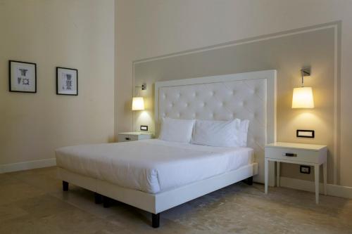 a bedroom with a white bed with two tables and two lamps at Hotiday Siracusa Floridia in Floridia