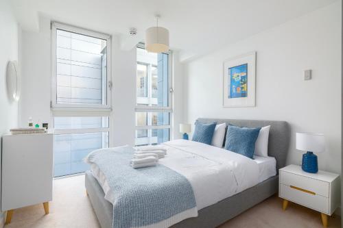 a white bedroom with a large bed with blue pillows at The Lambs Passage Executive Apartment in London