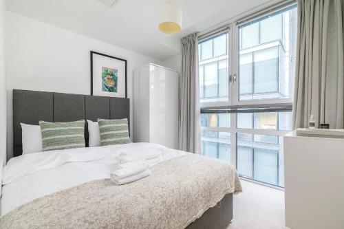 a bedroom with a white bed with a large window at The Lambs Passage Executive Apartment in London