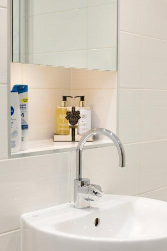 a bathroom with a sink and a mirror at The Lambs Passage Executive Apartment in London