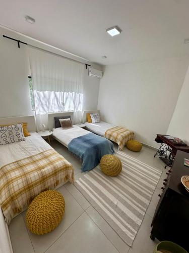 a bedroom with two beds and two ottomans at Chácara Segredo in Bonito